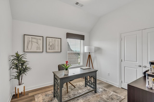 office space featuring visible vents, baseboards, lofted ceiling, and light wood-type flooring