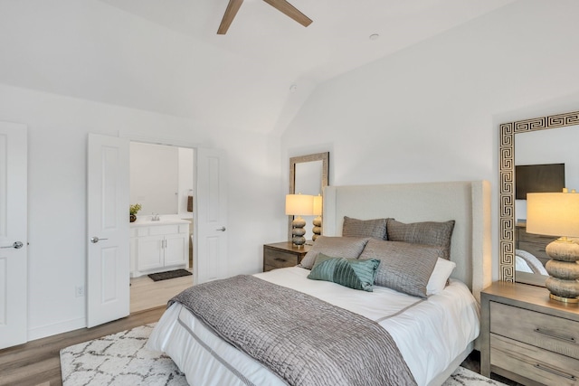bedroom featuring a sink, lofted ceiling, wood finished floors, connected bathroom, and a ceiling fan