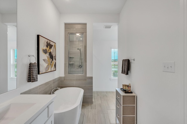 bathroom featuring vanity, visible vents, tile walls, tiled shower, and a soaking tub