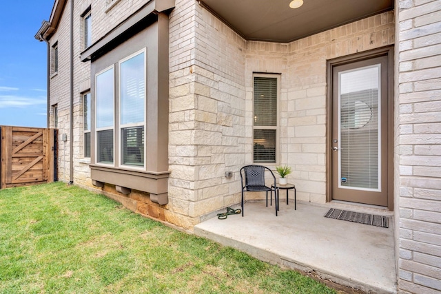 exterior space with fence, a gate, a yard, and stone siding