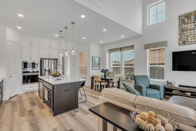 kitchen with a breakfast bar area, light countertops, white cabinetry, a sink, and stainless steel appliances