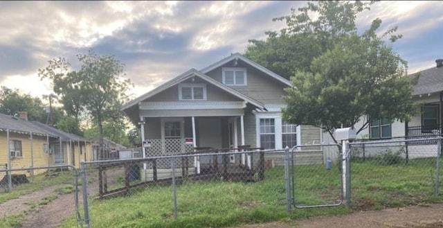 bungalow-style house featuring covered porch and a fenced front yard