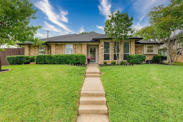 view of front of house with brick siding, fence, and a front yard