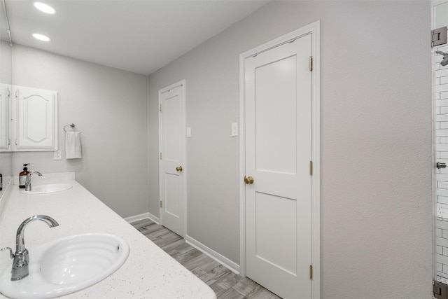bathroom with baseboards, a sink, wood finished floors, and double vanity
