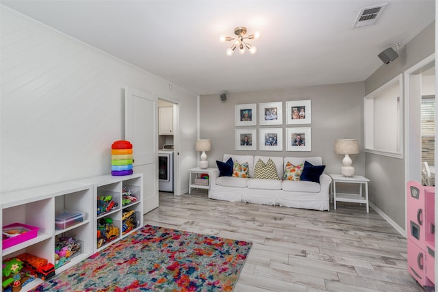 rec room featuring washer / dryer, an inviting chandelier, visible vents, and light wood-type flooring
