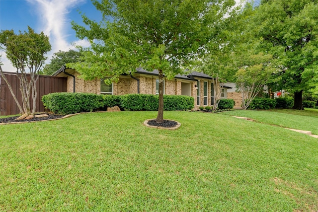 view of front of house with brick siding, fence, and a front lawn