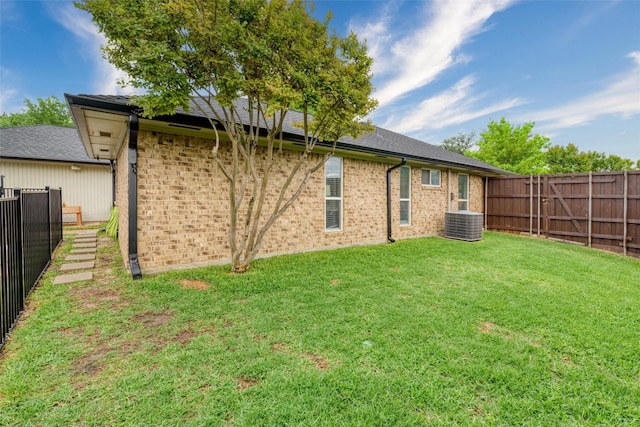 rear view of property with brick siding, a fenced backyard, a lawn, and cooling unit