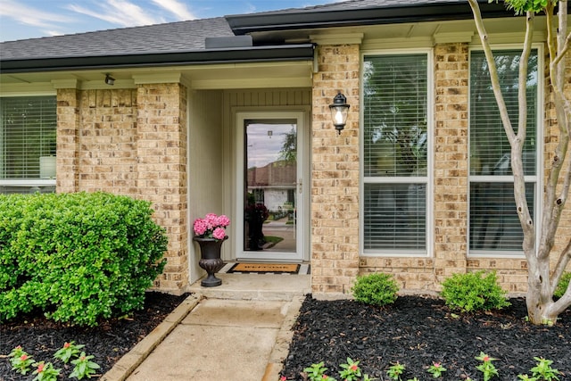 property entrance featuring brick siding and roof with shingles