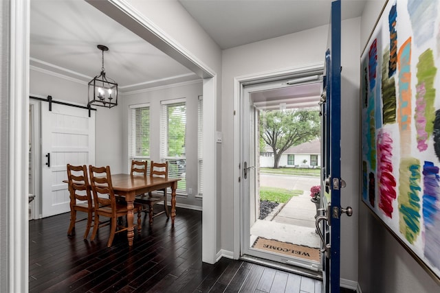 dining area featuring ornamental molding, baseboards, dark wood-type flooring, a barn door, and a chandelier