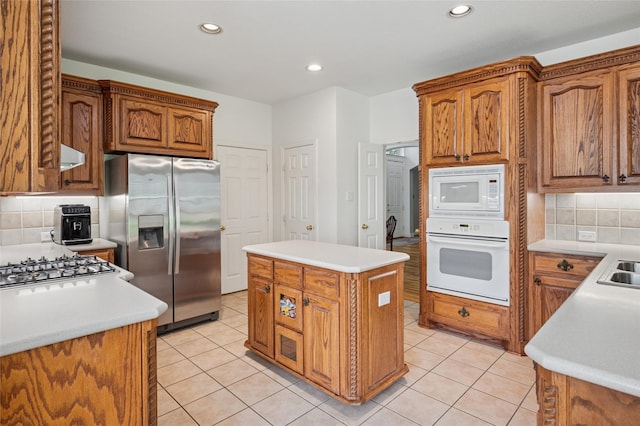 kitchen featuring light tile patterned floors, a center island, decorative backsplash, and white appliances