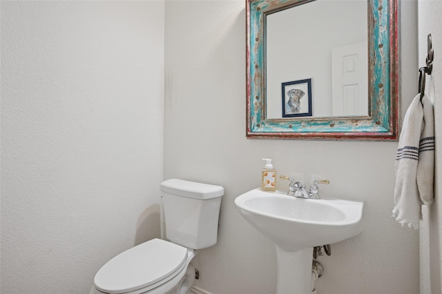 half bath featuring baseboards and toilet