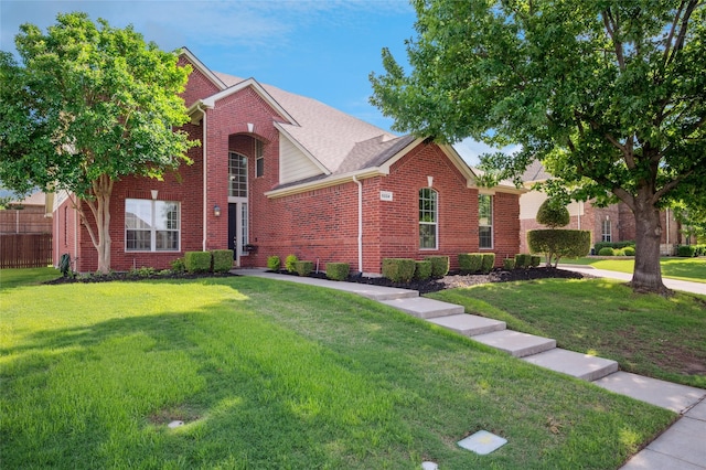 traditional home featuring fence, brick siding, and a front yard