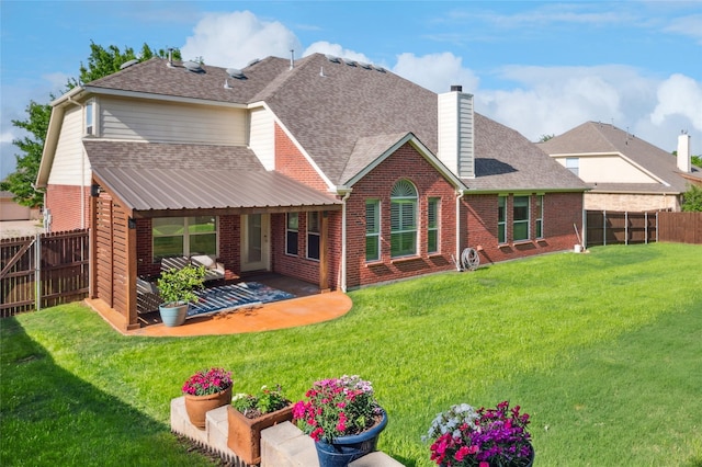 rear view of house with a fenced backyard, a chimney, a shingled roof, and brick siding