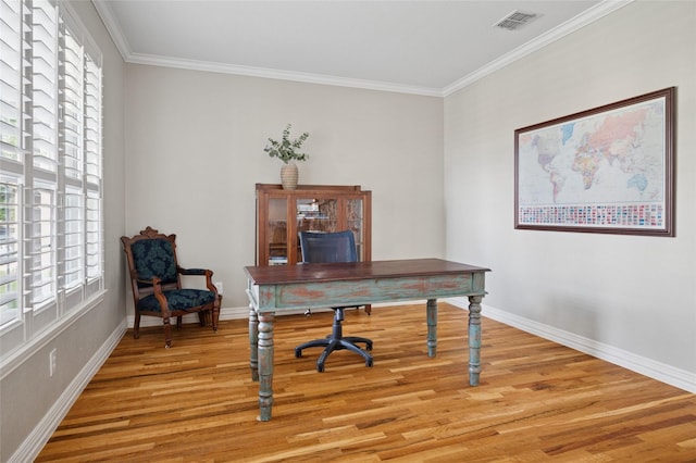 office space featuring crown molding, a healthy amount of sunlight, light wood-type flooring, and visible vents