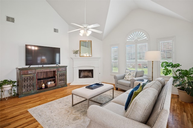 living room featuring ceiling fan, a fireplace, wood finished floors, and visible vents