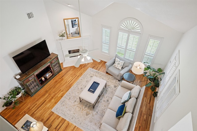 living area featuring high vaulted ceiling, visible vents, and wood finished floors