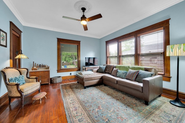 living area featuring wood-type flooring, a ceiling fan, baseboards, and crown molding