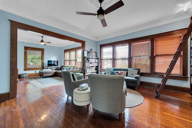 living room featuring crown molding, baseboards, ceiling fan, and wood-type flooring