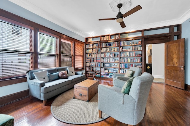 living room featuring baseboards, ornamental molding, wood-type flooring, and a ceiling fan