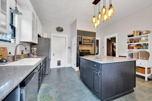 kitchen featuring white cabinetry, a chandelier, a sink, decorative light fixtures, and stainless steel appliances