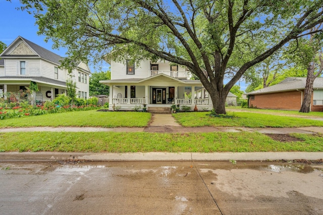 american foursquare style home with covered porch and a front yard