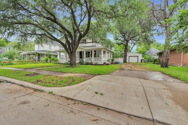 view of front of house with covered porch, driveway, a detached garage, an outdoor structure, and a front lawn