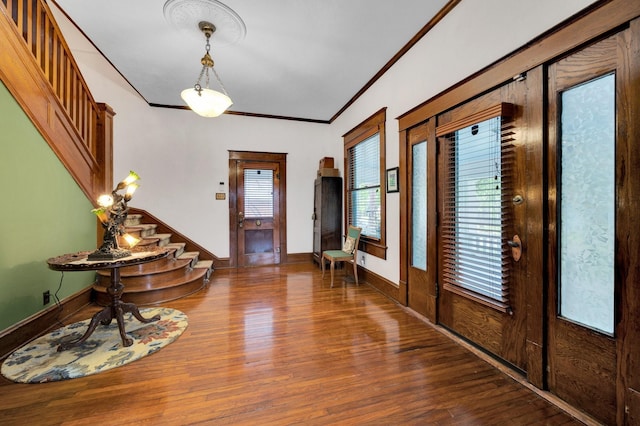 entryway with baseboards, ornamental molding, stairs, and wood finished floors