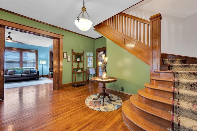 staircase featuring crown molding, baseboards, and wood finished floors