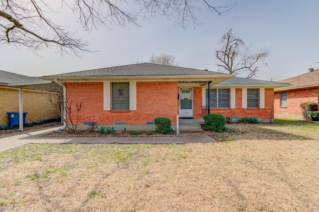 view of front of home featuring brick siding, a shingled roof, a front lawn, and crawl space