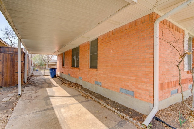 view of side of property with fence, an attached carport, brick siding, and crawl space