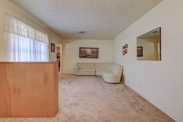 unfurnished living room featuring carpet floors, a textured ceiling, and baseboards