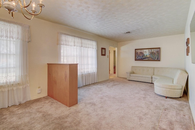 unfurnished living room featuring carpet flooring, a notable chandelier, and a textured ceiling
