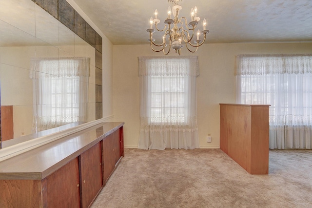 unfurnished dining area with carpet floors, baseboards, and a chandelier