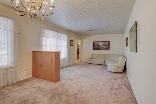 unfurnished living room with electric panel, a textured ceiling, carpet floors, baseboards, and a chandelier