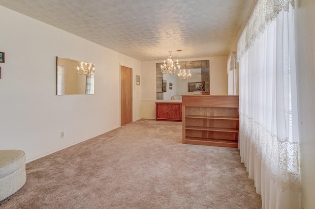 interior space with an inviting chandelier, a textured ceiling, and light carpet