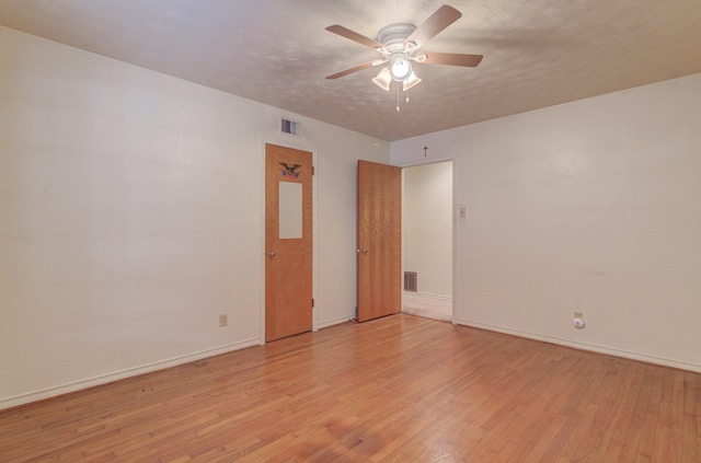 empty room featuring light wood-style floors, baseboards, ceiling fan, and visible vents