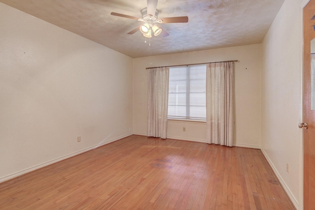 spare room featuring light wood-style flooring, baseboards, and a ceiling fan