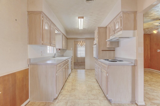 kitchen featuring under cabinet range hood, white appliances, light countertops, and light brown cabinets