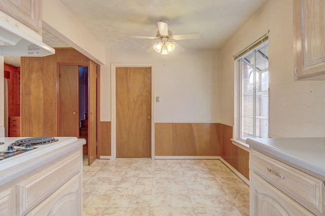kitchen featuring under cabinet range hood, light countertops, wainscoting, and ceiling fan