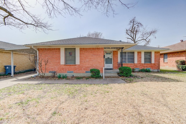 view of front of home featuring brick siding, a shingled roof, a front lawn, and crawl space