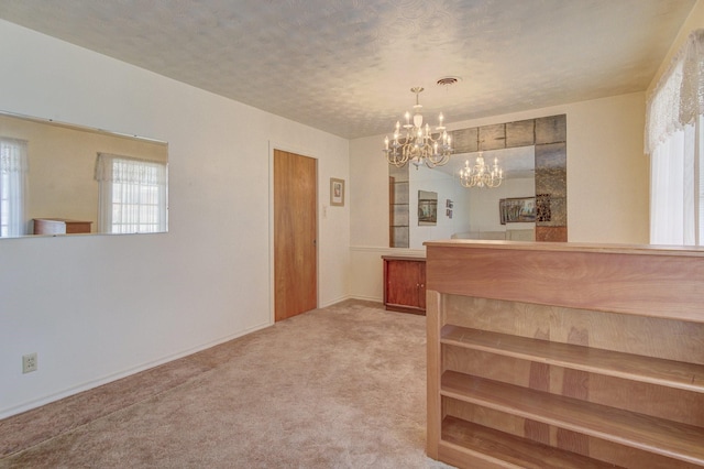 interior space with light carpet, a textured ceiling, a notable chandelier, and baseboards
