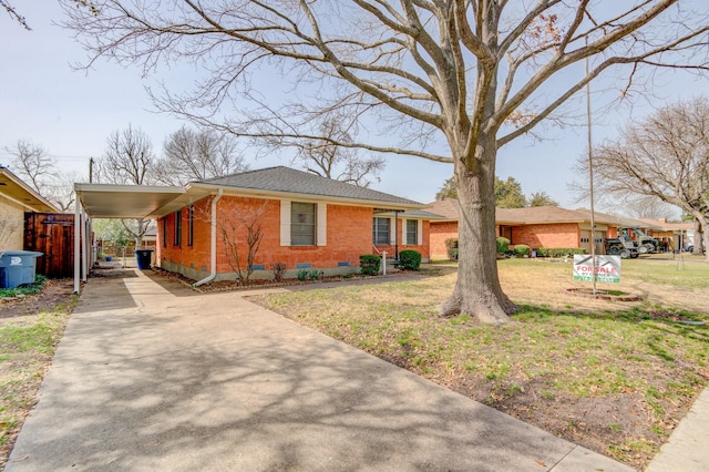 view of front of property with brick siding, a front yard, crawl space, concrete driveway, and a carport