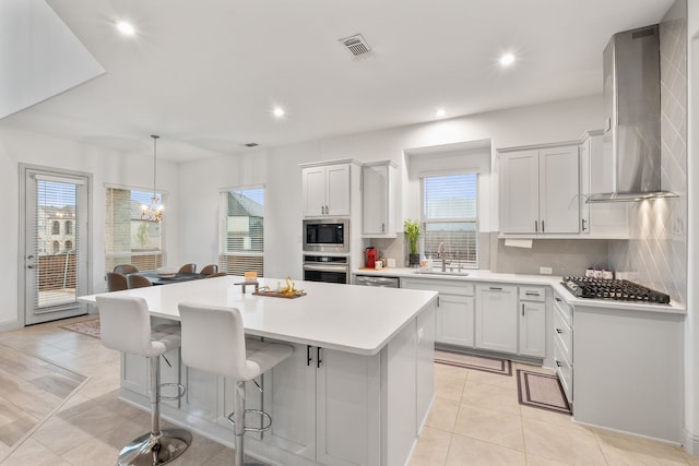 5617 Winona Ln, Mckinney, TX 75071 - kitchen featuring wall chimney exhaust hood, stainless steel appliances, a kitchen island, a chandelier, and backsplash