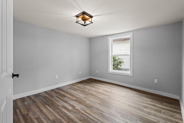 unfurnished room with baseboards and wood finished floors