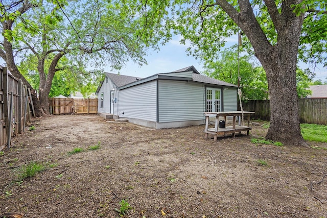 back of house with a fenced backyard, a shingled roof, and french doors