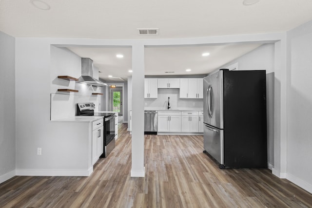 kitchen featuring wall chimney range hood, appliances with stainless steel finishes, and light wood-type flooring