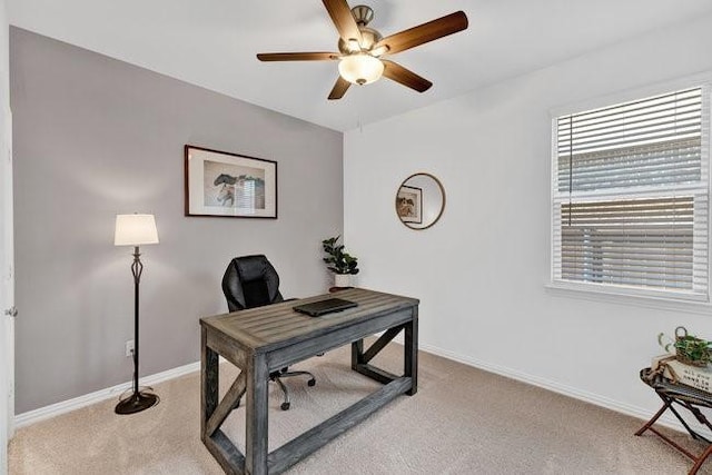 office space with a ceiling fan, baseboards, and light carpet