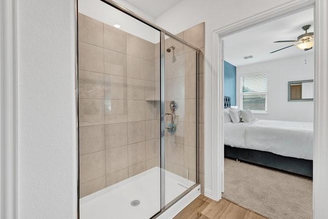 ensuite bathroom with ensuite bathroom, a ceiling fan, wood finished floors, and a shower stall