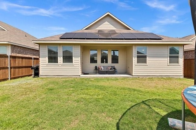 back of property featuring outdoor lounge area, a fenced backyard, a patio area, a yard, and solar panels