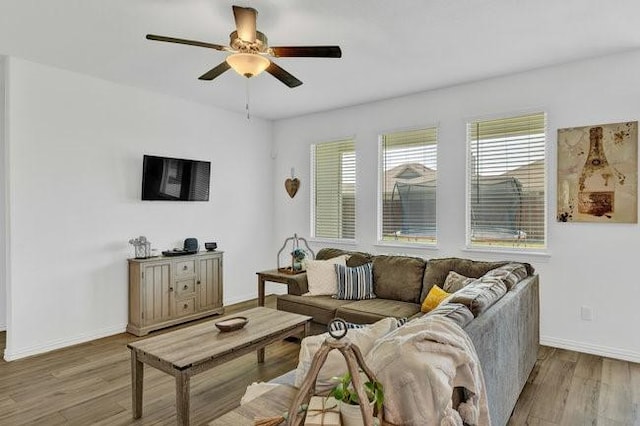 living area featuring a ceiling fan, baseboards, and wood finished floors